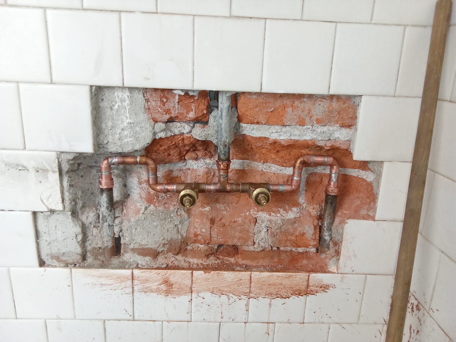 Instalación de tuberías expuestas en pared de azulejos